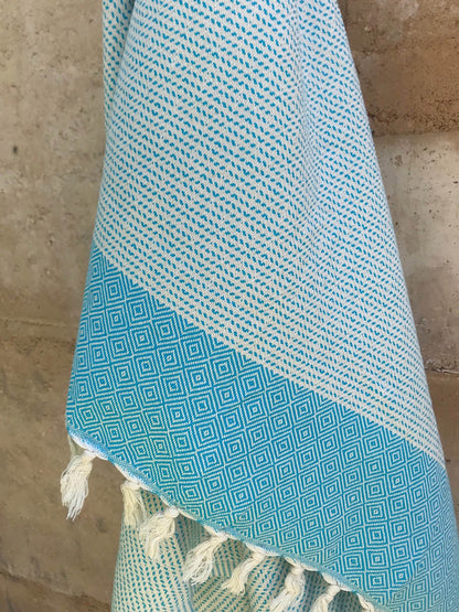 Freostyle Turkish Beach Towel with Pockets, Capri, Aqua Blue, hung on wall